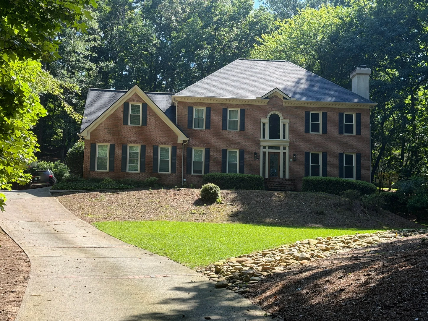 A brick home and front yard before a landscaping concept